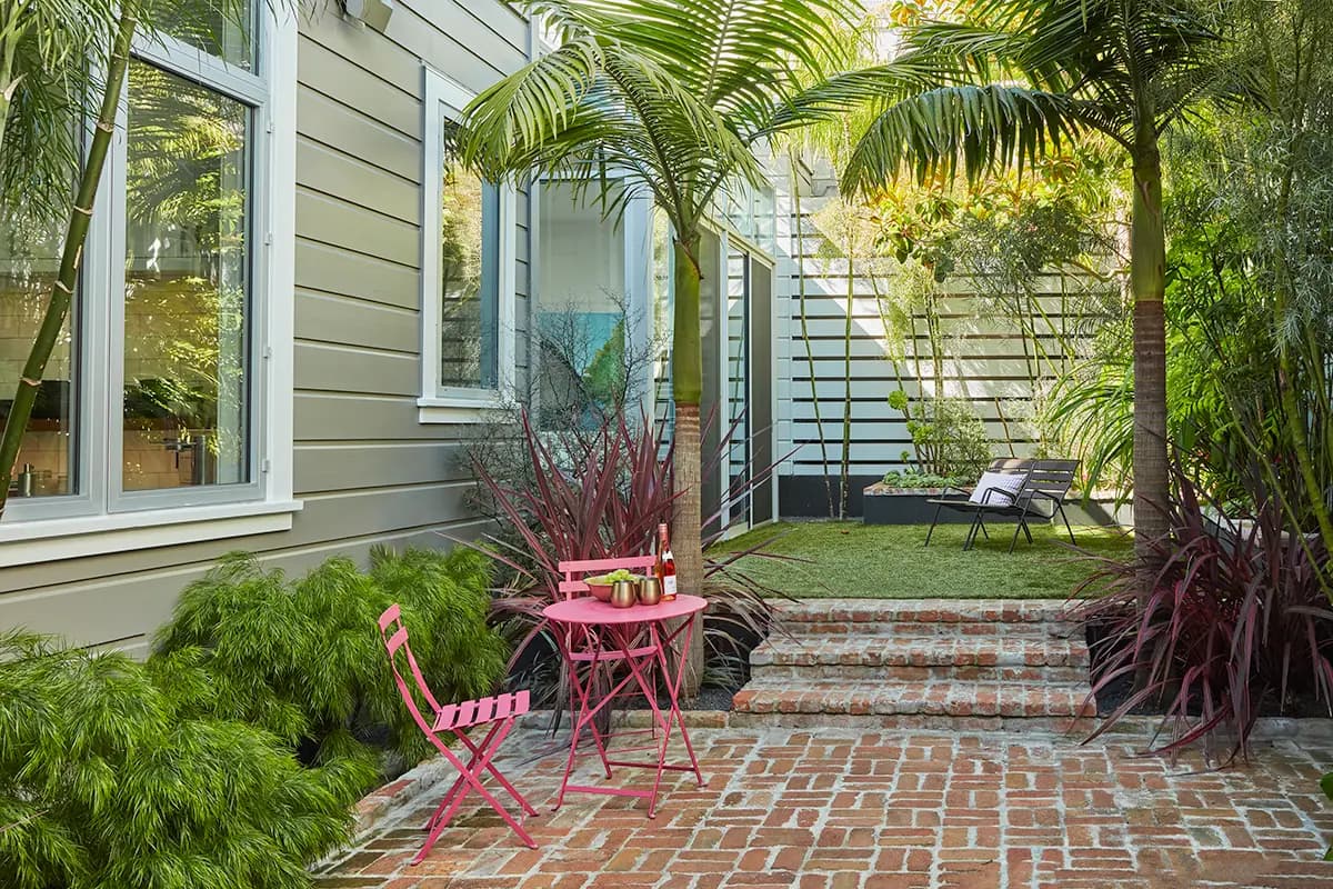 Flora Grubb Gardens: comedor al aire libre con Chamaedorea plumosa y king palms